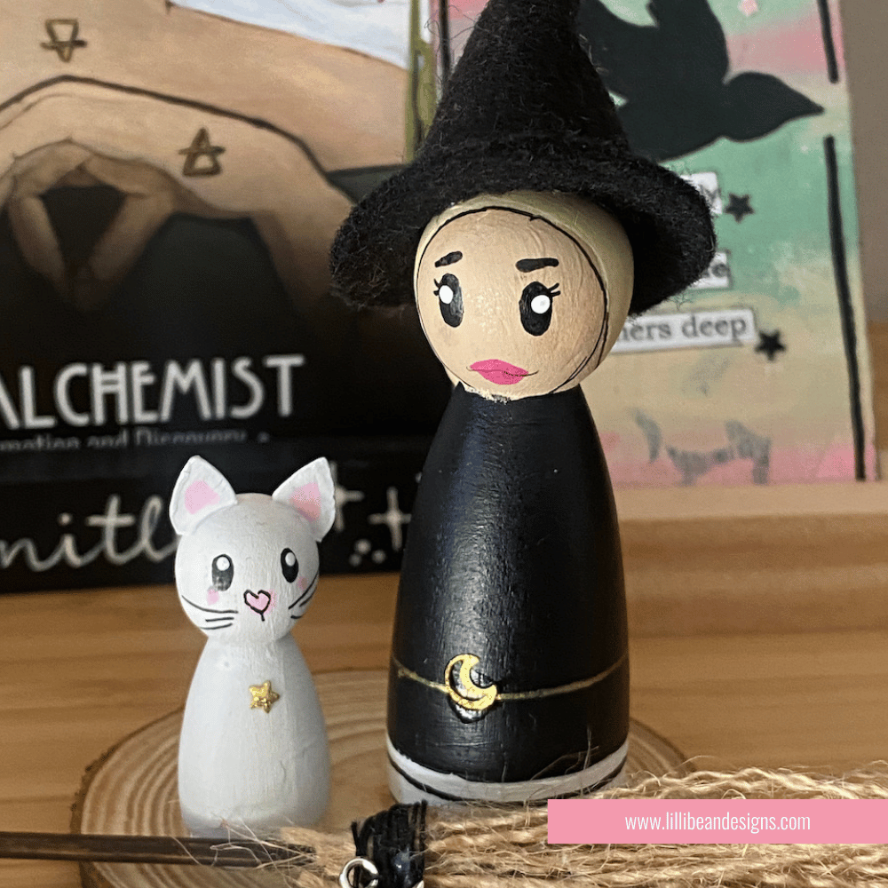 Wooden peg doll of a witch and a cat with a blurred background